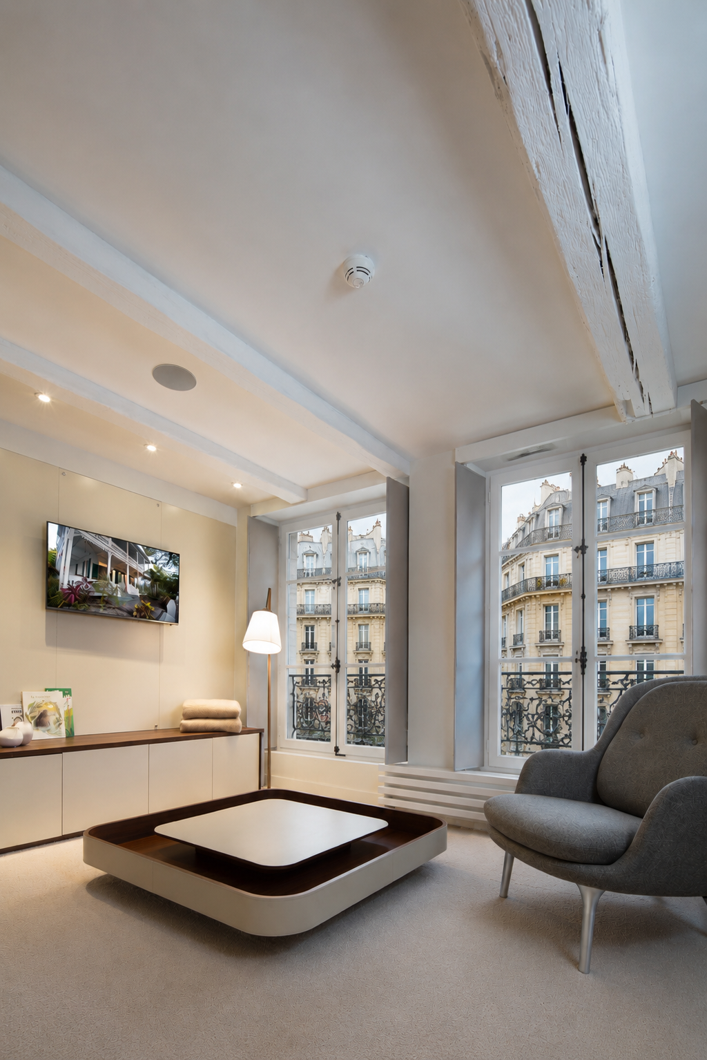 Salon parisien achev&eacute;, poutres apparentes et fen&ecirc;tres &agrave; la fran&ccedil;aise sur l&rsquo;haussmannien.